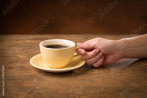 hand holding a coffee cup on a wooden table