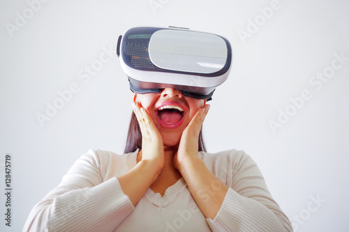 Young brunette woman wearing virtual reality goggles experiencing future technology  interacting and smiling while playing  studio background  vr concept