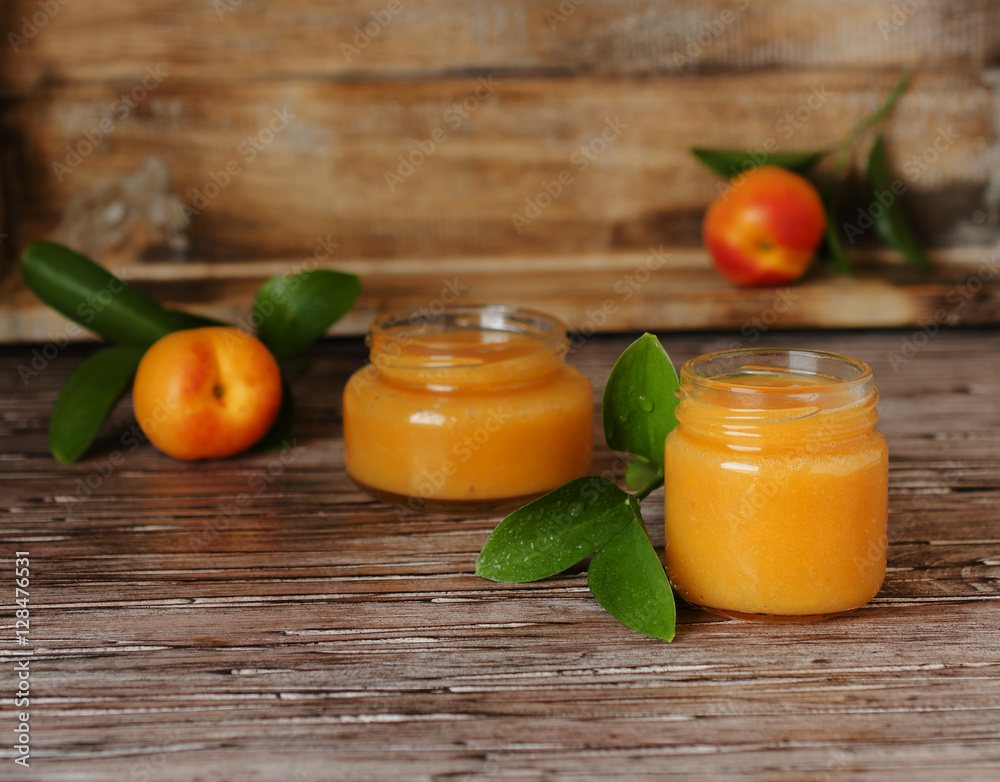 Apricot jam in small glass jars with fruits, selective focus