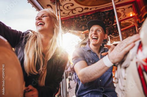Smiling couple on carousel at fairground photo