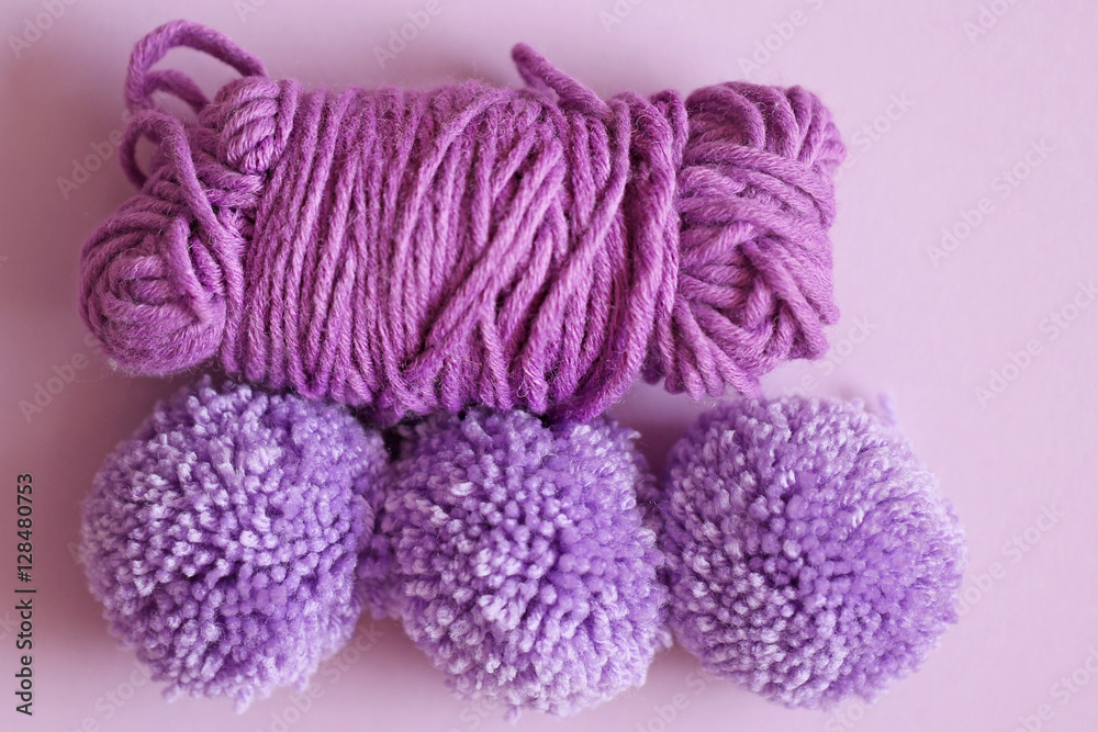 three woolen pompoms on a purple background