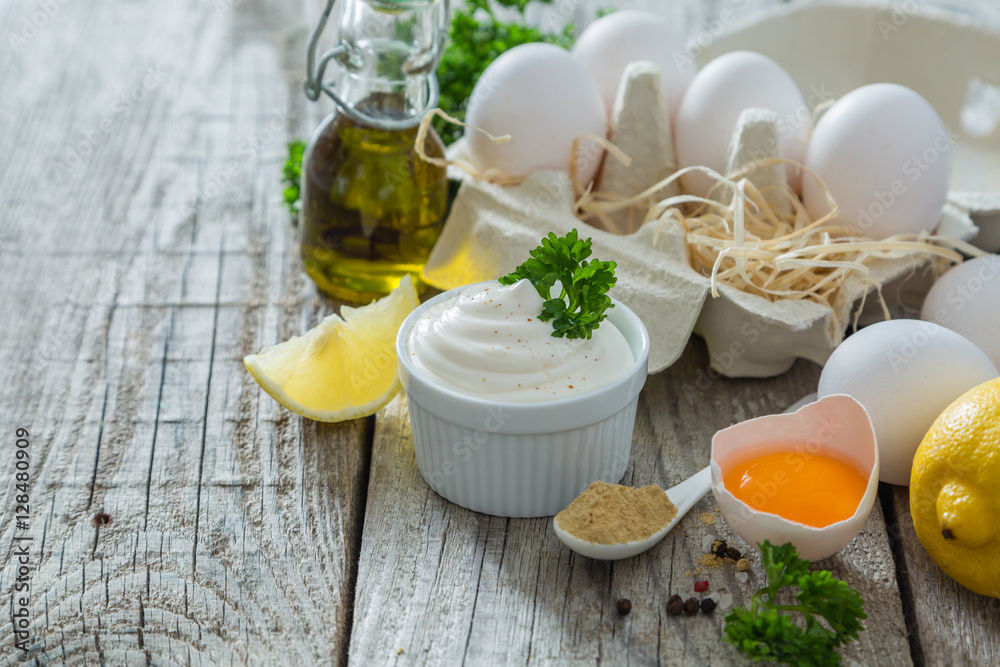 Mayonnaise sauce and ingredients on wood background