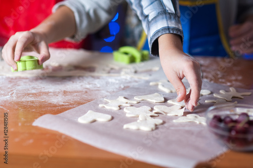 hands of a child who is preparing cookies in the kitchen with flour and dough