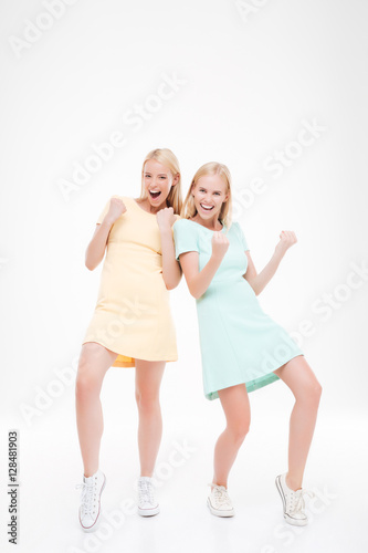 Two ladies makes winner gesture over white background