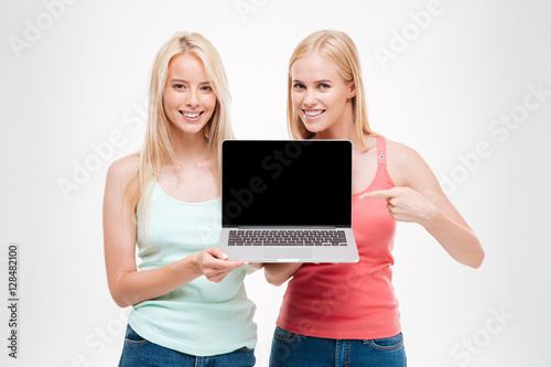 Two young women showing the laptop