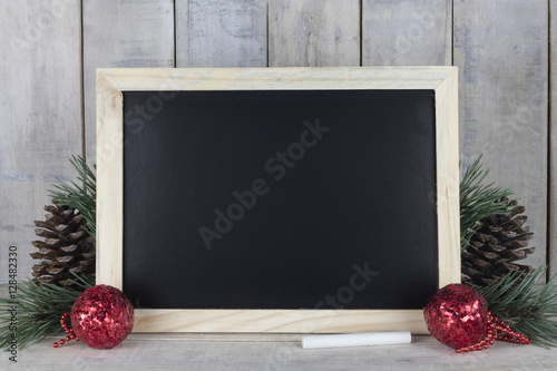 Empty chalkboard with christmas decoration on a wooden background. Any text or drawing might be placed on it.