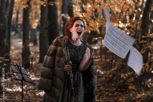 Young emotional woman throwing away the musical sheets and holding an oboe in hand