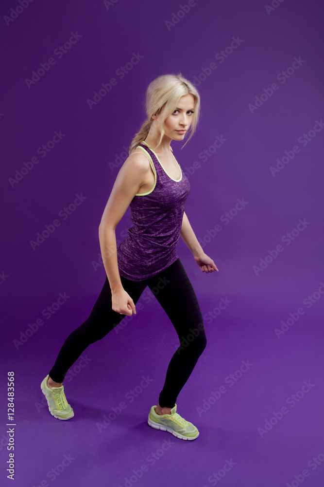 Beautiful young girl in a pose runner. Studio background, purple