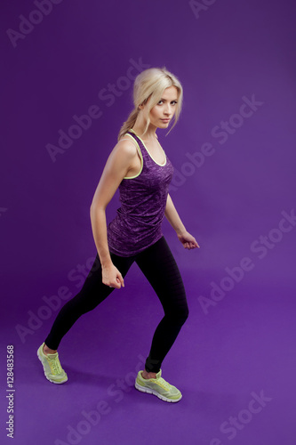 Fototapeta Naklejka Na Ścianę i Meble -  Beautiful young girl in a pose runner. Studio background, purple