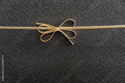 Gold double elastic holiday bow on black textured background