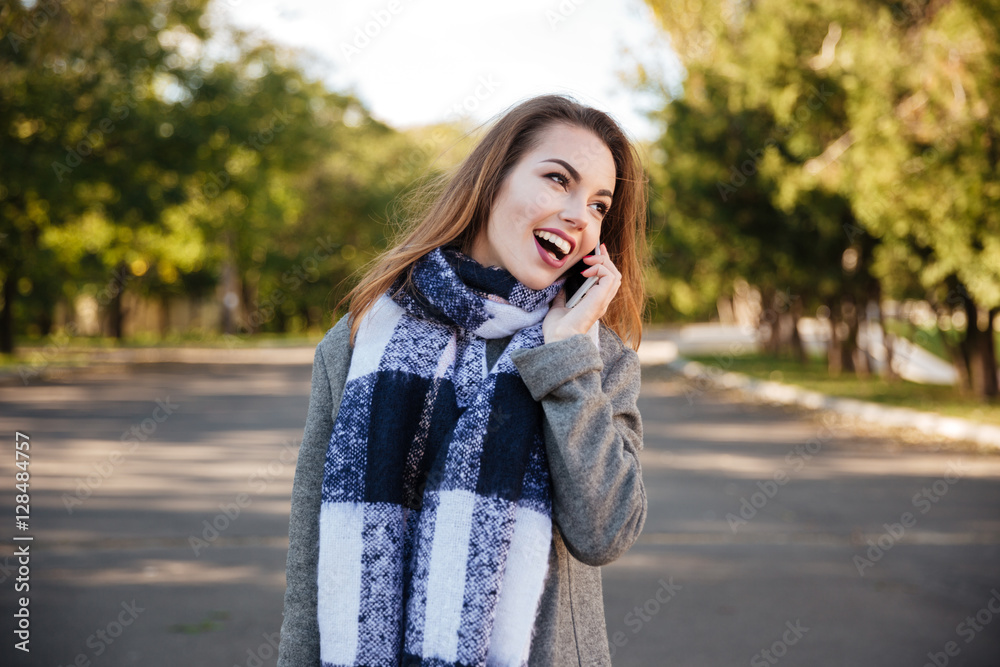 Young happy woman wearing scarf talking on telephone
