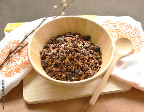 Home made cocoa granola with oats, chia seeds, flax seeds, almonds and raisins on a wood bowl