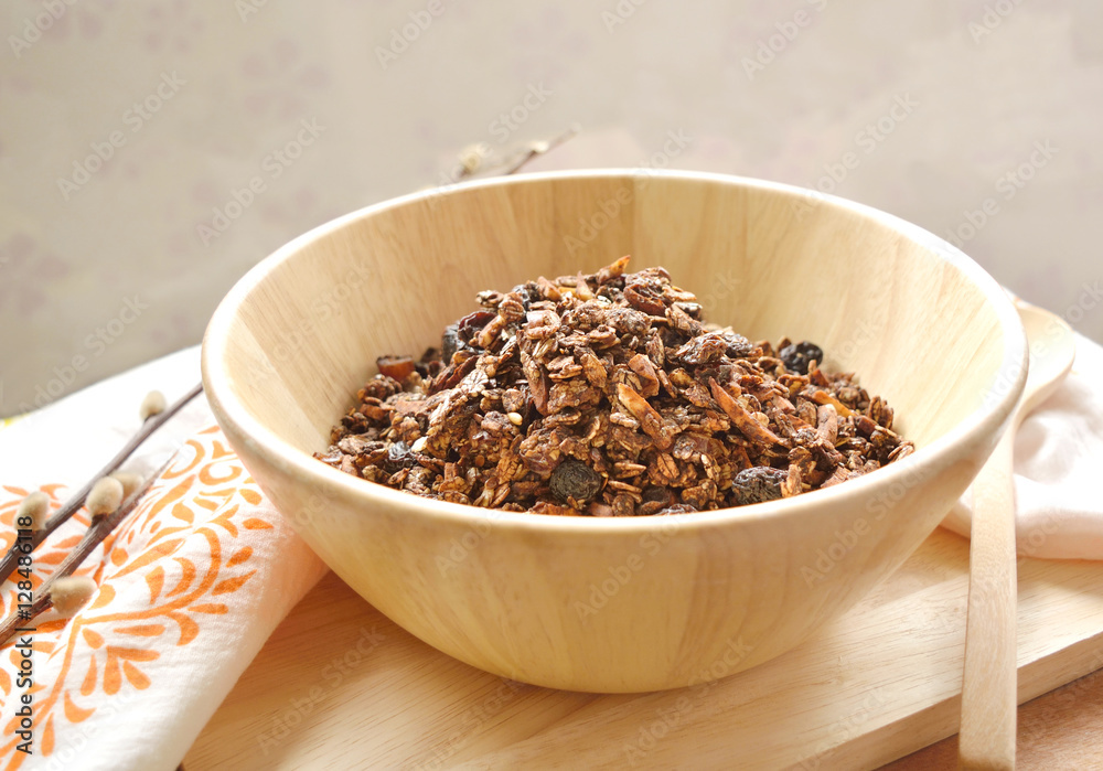 Home made cocoa granola with oats, chia seeds, flax seeds, almonds and raisins on a wood bowl