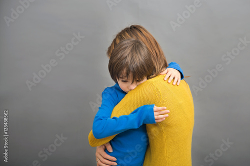 Sad little child, boy, hugging his mother at home, isolated imag