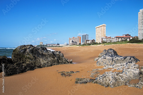  Empty Rocky Beach Against City Skyline and Blue Sky