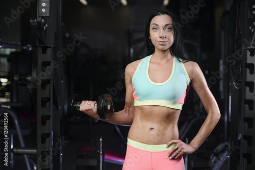 Athletic young woman posing and doing fitness workout with weigh