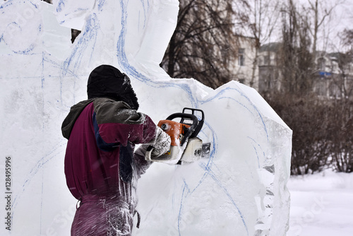 Worker using chainsaw carving an ice sculpture
