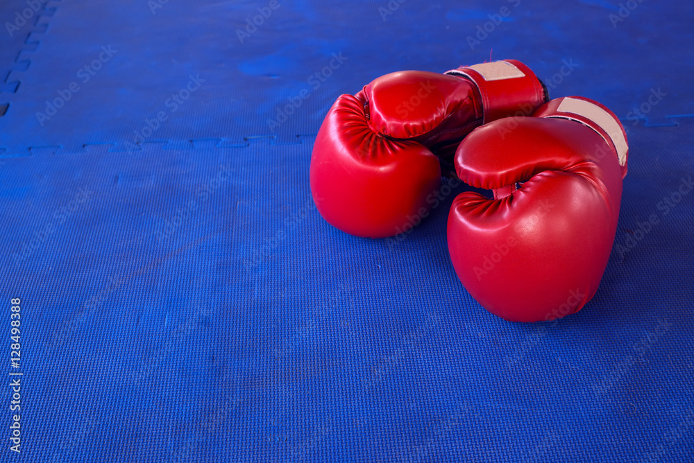 Pair of Red boxing gloves hanging on a Blue wall