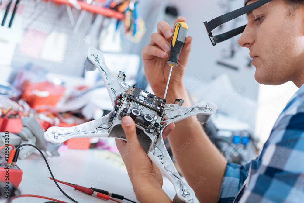 Handsome man repairing drone with screwdriver