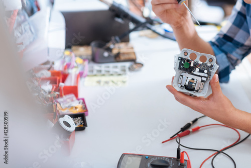 Close up of young man repairing drones chip with screwdriver