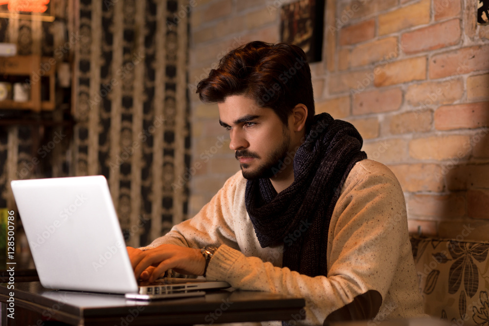 Young man sitting in a cafe and working on his laptop.