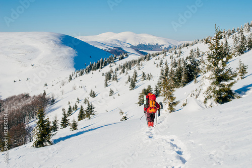 A tourist in a red clothes with a backpack travels high winter C