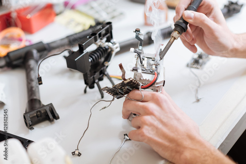 Detailed close up of mans hands soldering drone chips