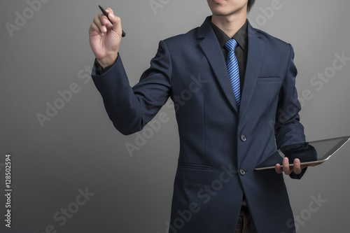 Close up of businessman in blue suit drawing on gray background