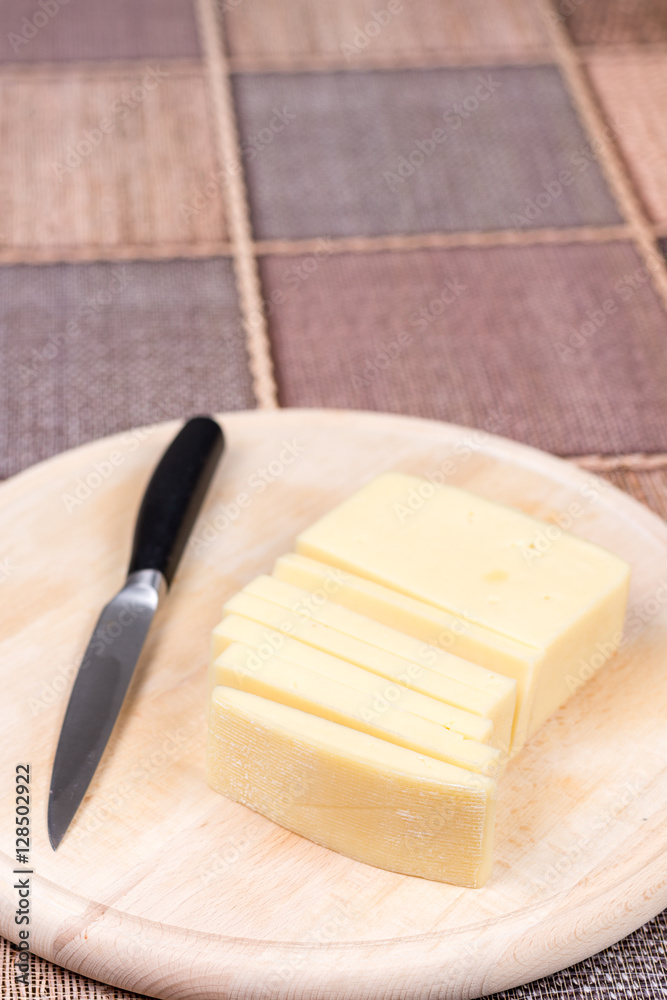 Sliced yellow pizza cheese on the wooden cutting board