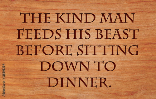 The kind man feeds his beast before sitting down to dinner - Hebrew Proverb on wooden red oak background