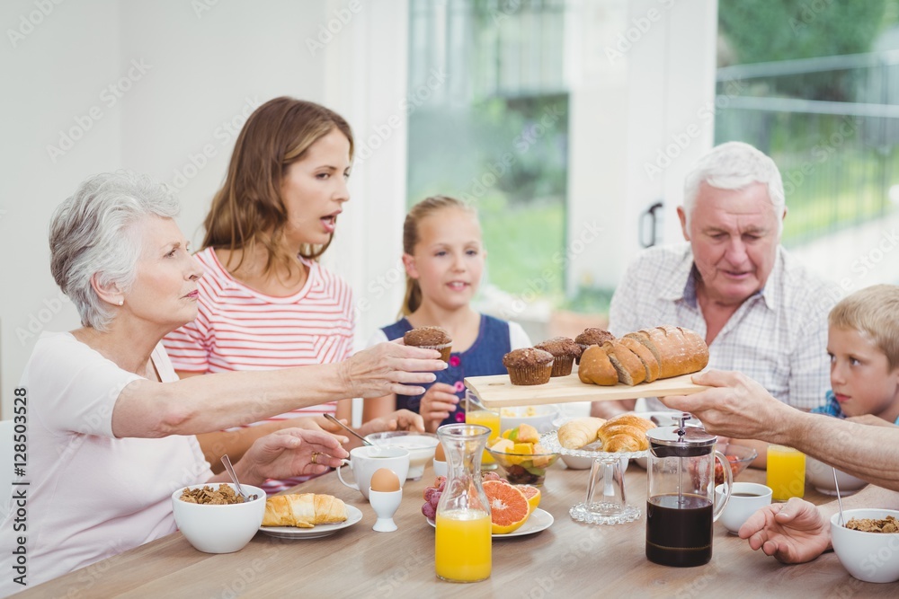 Multi-generation family having muffins during breakfast