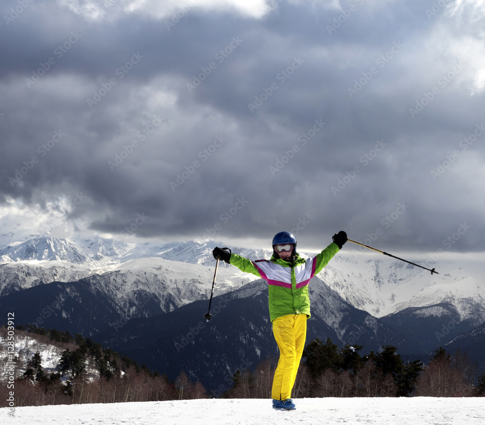 Happy young skier with ski poles in sun mountains