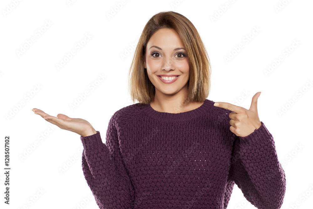 young beautiful woman in a purple sweater and jeans, holding imaginary object on the palm young beautiful woman in a purple sweater and jeans, holding imaginary object on the palm