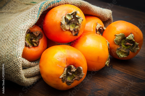 Delicious fresh persimmon fruit on wooden table photo