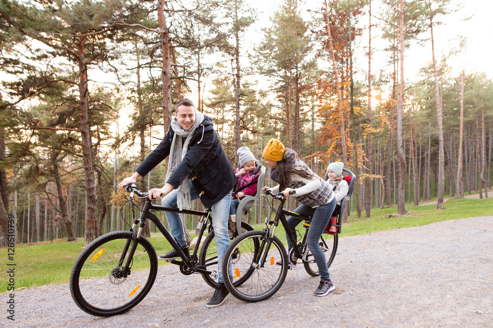 Obraz premium Young family in warm clothes cycling in autumn park