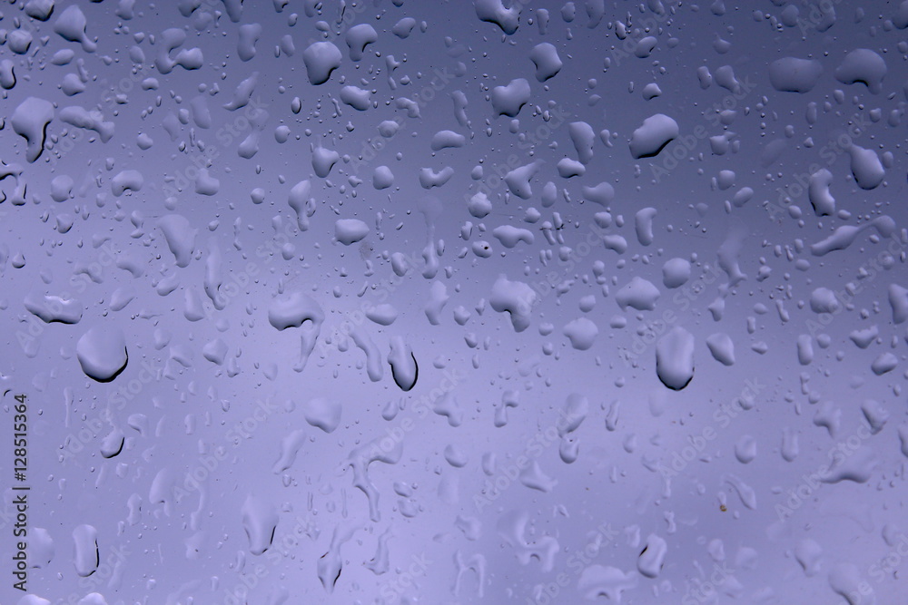 Water drops against blue background, wet glass surface car.