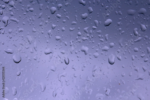 Water drops against blue background, wet glass surface car.