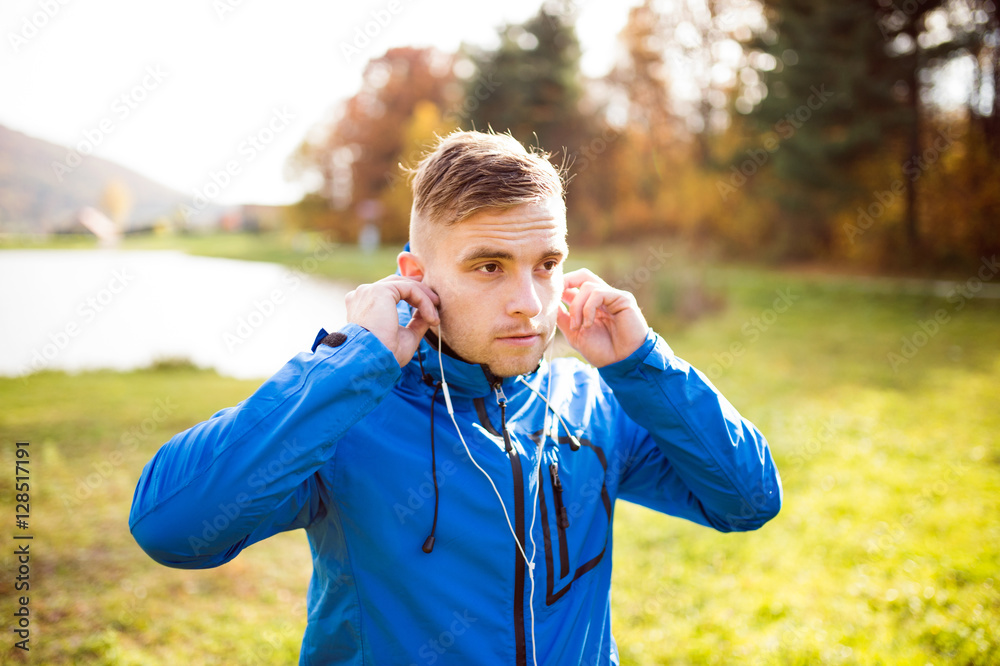 Naklejka premium Young runner with earphones outside in sunny autumn nature