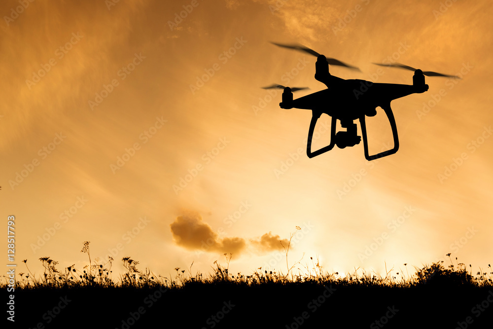 Silhouette of hovering drone taking pictures of nature at sunset