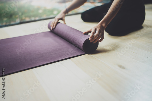 Close up view of female hands.Gorgeous young woman practicing yoga indoor. Beautiful girl preparing mats for practice class.Calmness and relax, happiness concept.Horizontal, blurred background.
