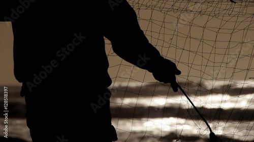 Fishermen silhouette working and repairing a fishing net