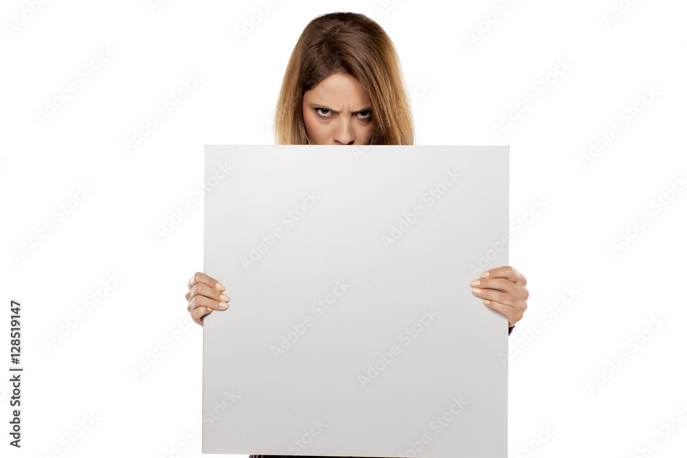 young angry woman peeking behind blank board for advertising young angry woman peeking behind blank board for advertising