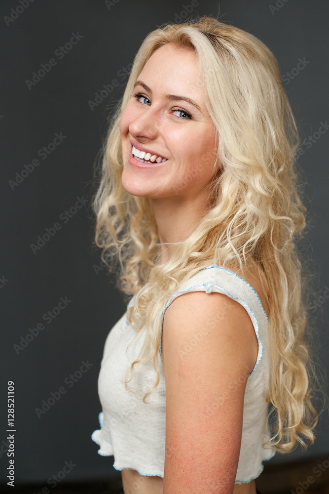 Beautiful blonde woman smiles broadly, gray background