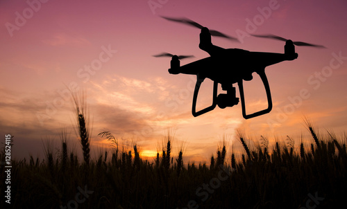 Silhouette of hovering drone taking pictures of nature at sunset