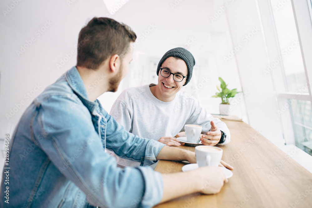 Men are sitting in front of the table near window Men are sitting in front of the table near window
