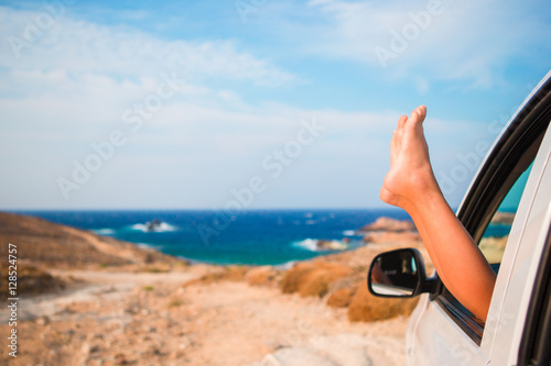 Close up of little girl feet showing from car window background sea