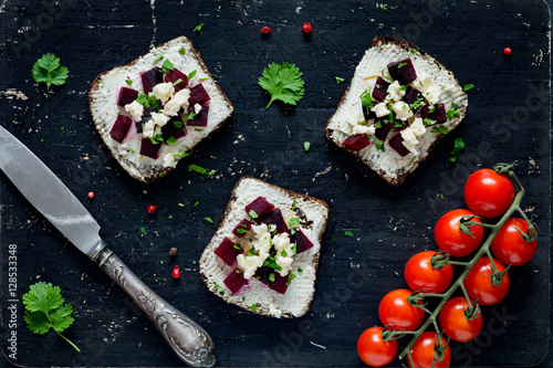 Goat cheese, roasted beet and feta cheese appetizer sandwiches on black cutting board, top view