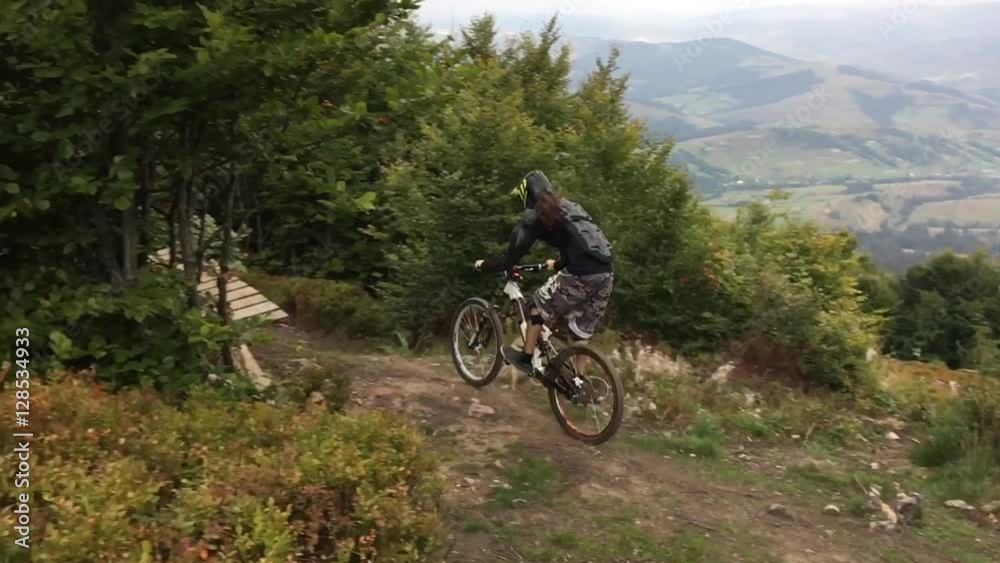 Downhill cyclist rides along a mountain trail and calls in on a trampoline Downhill cyclist rides along a mountain trail and calls in on a trampoline