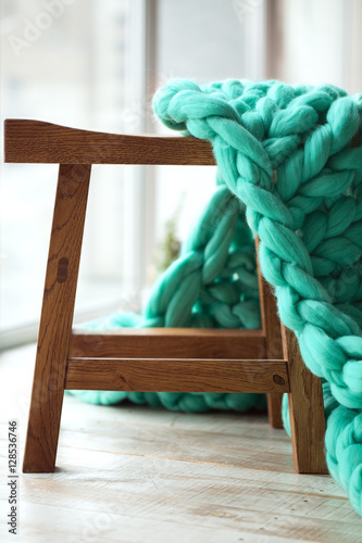 Green knitted merino wool blanket on wooden chair © riakhinantonUkraine