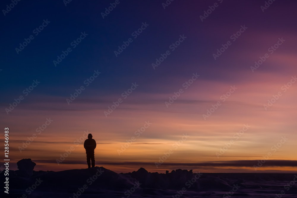 Silhouette of person watching sunset over Antarctica